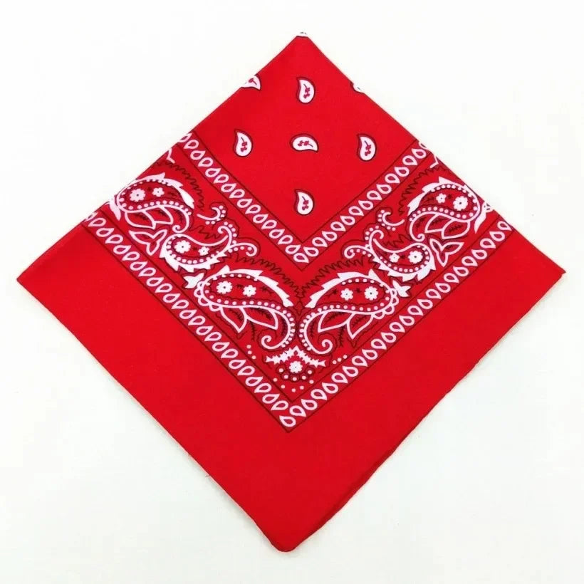 A red cotton bandana scarf featuring white paisley embroidery on a square fabric.
