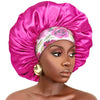 A model wears a vibrant pink satin sleep bonnet with an elastic band on her head.