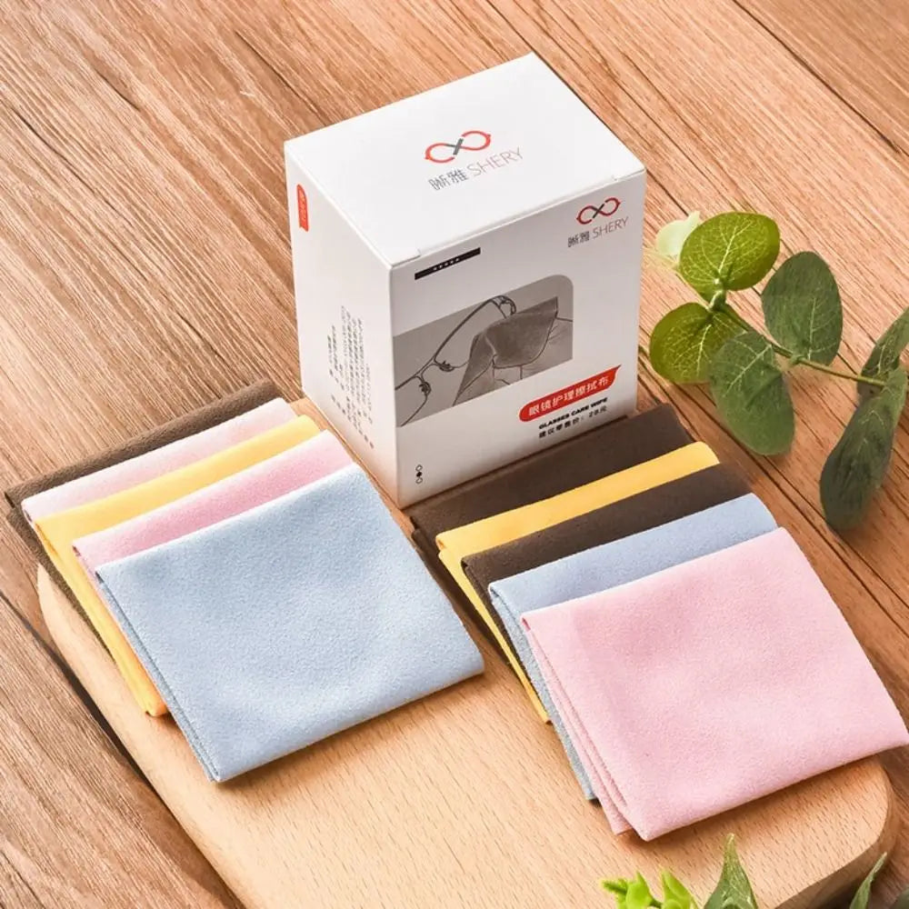 Un juego de paños de limpieza de ante multicolor para gafas, empaquetado en una caja blanca y exhibido sobre una superficie d