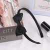 Black grosgrain ribbon hair bow with a long strap displayed next to a box and a glass.