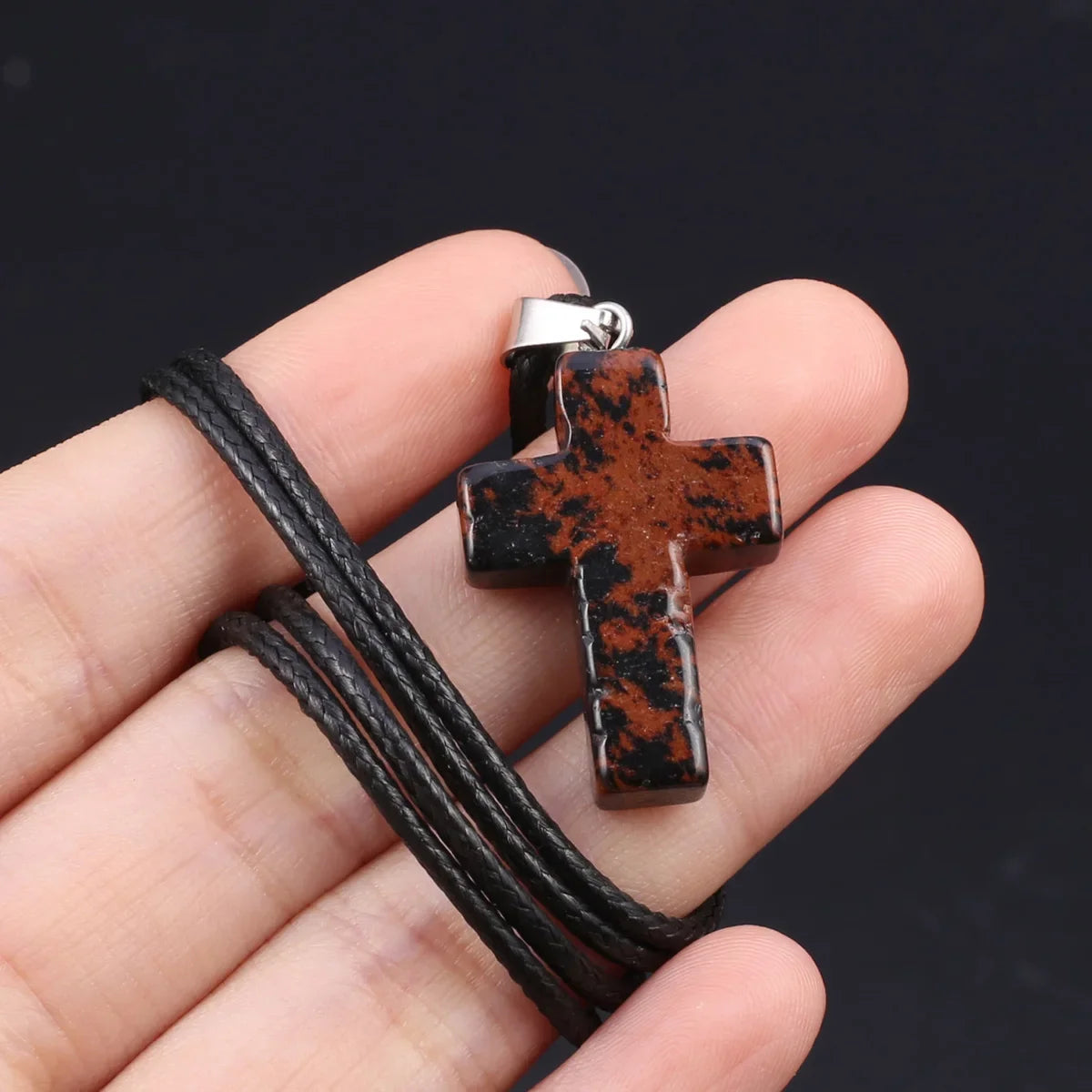 Schwarzes Tigerauge-Agat-Kreuz-Anhänger-Halskette in der Hand