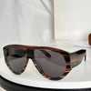 Brown tortoiseshell oversized pilot sunglasses resting on a white surface.