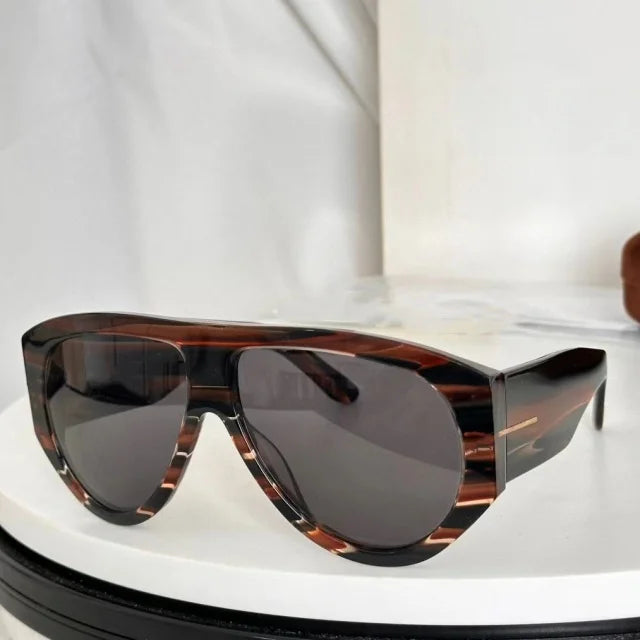 Brown tortoiseshell oversized pilot sunglasses resting on a white surface.
