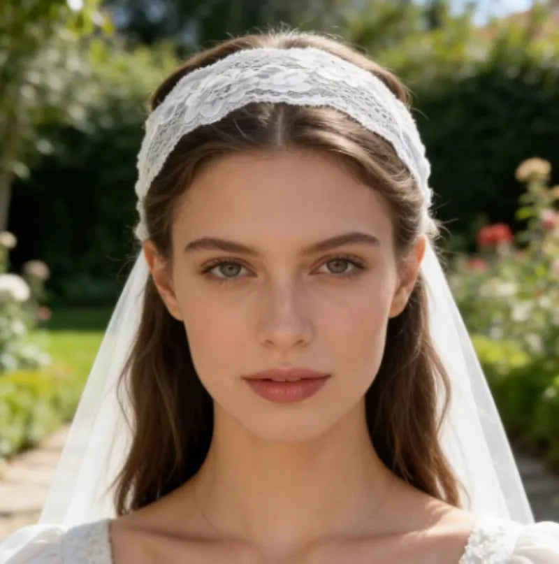 A close-up portrait of a woman wearing a white floral lace hair headband and veil outdoors.