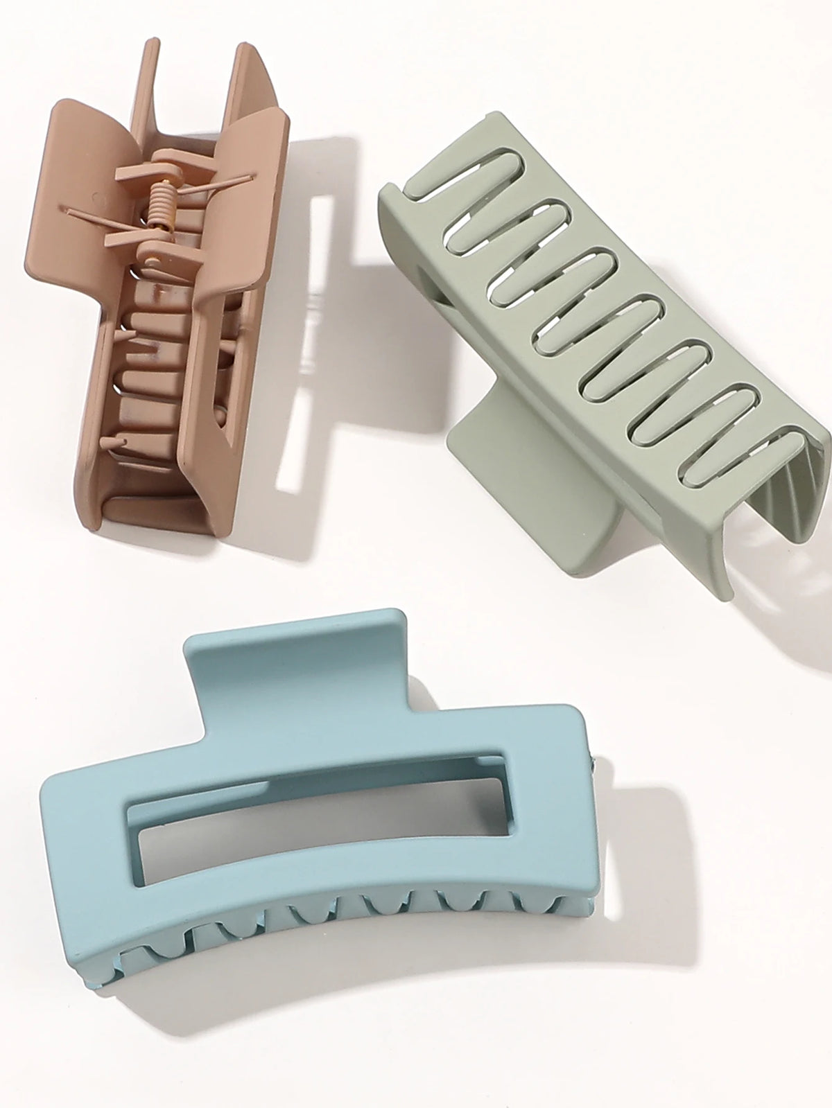 A set of seven square hair claw clips in various shades of beige and green, shown from different angles.