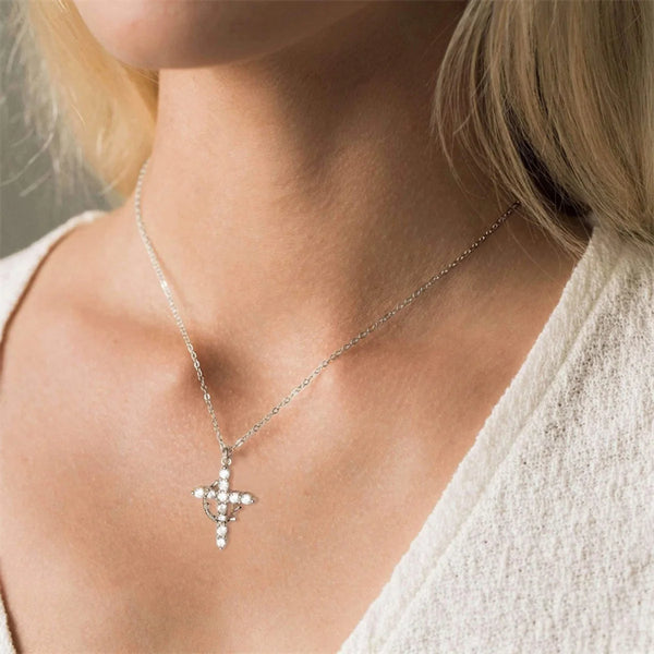 Pendentif de croix en acier inoxydable argenté porté autour du cou sur peau claire.