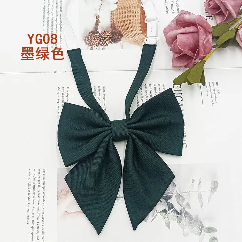 A dark green solid cotton bow tie tied in a bow shape, displayed on a white background with floral elements.