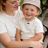 A woman is holding a young boy wearing a beige letter print sun hat.