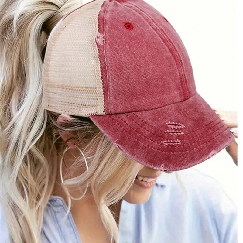 A close-up of a vintage mesh baseball cap in maroon and beige colors worn by a blonde woman.