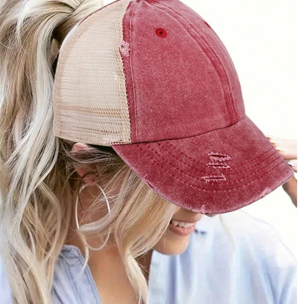 A close-up of a vintage mesh baseball cap in maroon and beige colors worn by a blonde woman.
