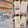 A display of pearl and black bead brooch pins for customizing apparel shown against a denim background.