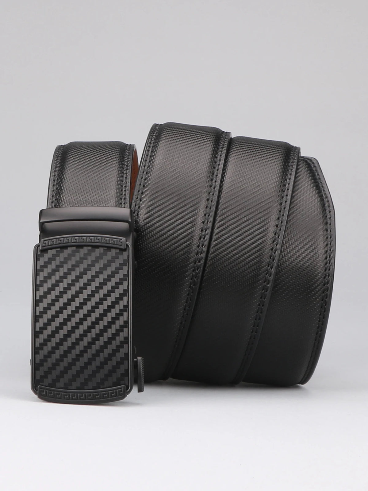 A black men's genuine leather ratchet dress belt coiled and displayed on a light gray background.