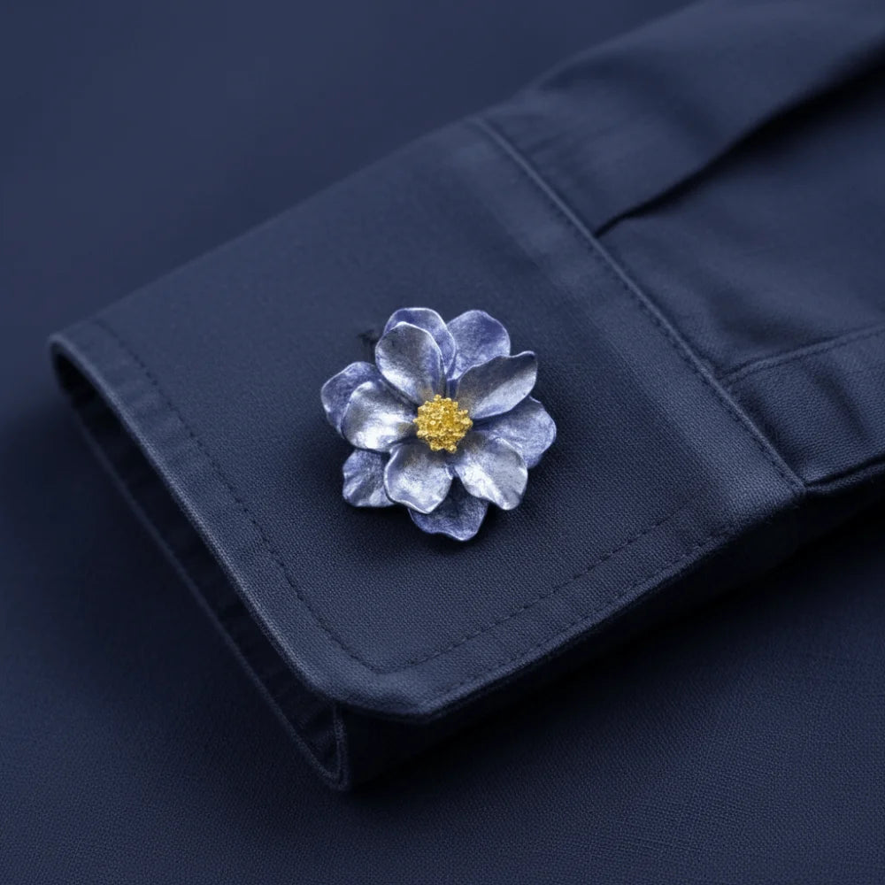 A dark blue fabric button cover featuring a pressed, silvery-blue flower with a gold center.