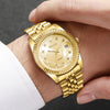 A gold-toned wristwatch with a round face and bracelet is being held on a person's wrist.