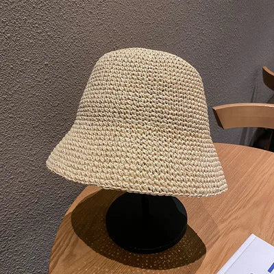 A light beige hand-woven straw visor hat displayed on a wooden table.