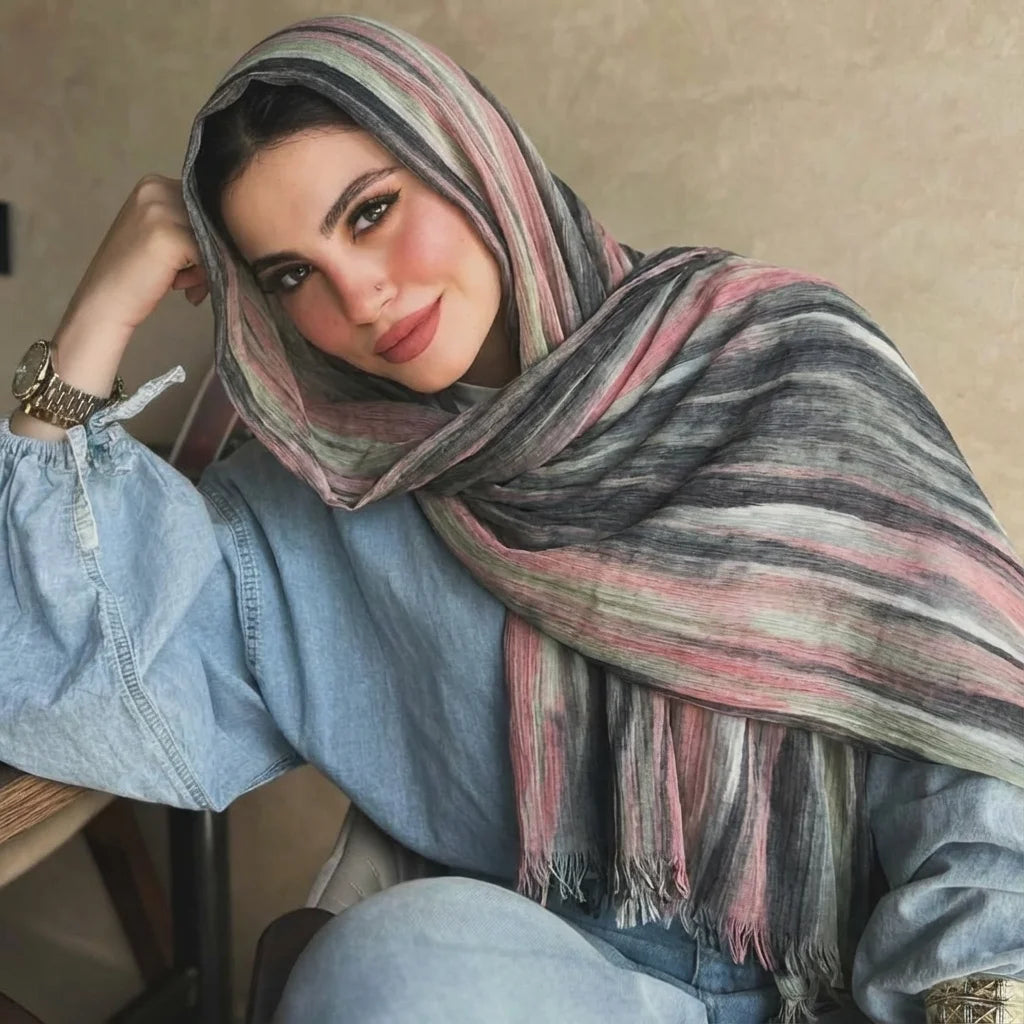 Una mujer vistiendo un pañuelo hijab rayado y multicolor sobre su cabeza y hombros.
