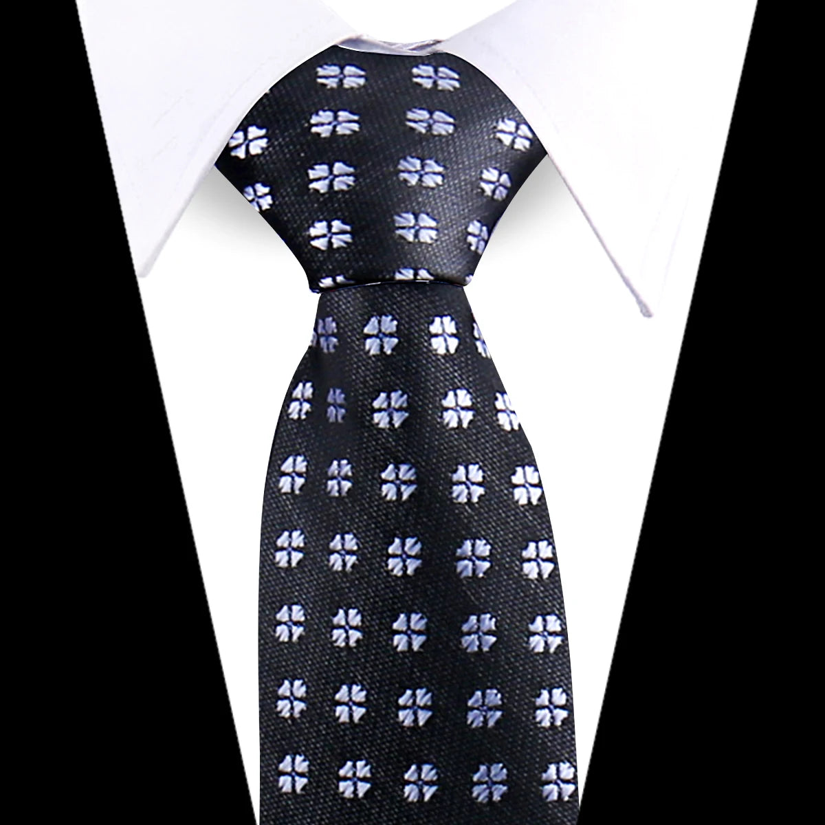 Black silk necktie with a silver floral paisley pattern worn under a white dress shirt.