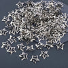 A pile of silver star metal snap hair clips scattered on a dark surface.