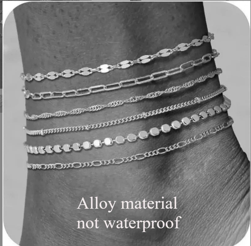 Ein Set dünner, miteinander verbundener Knöchelarmbänder aus Legierung an einem Knöchel.