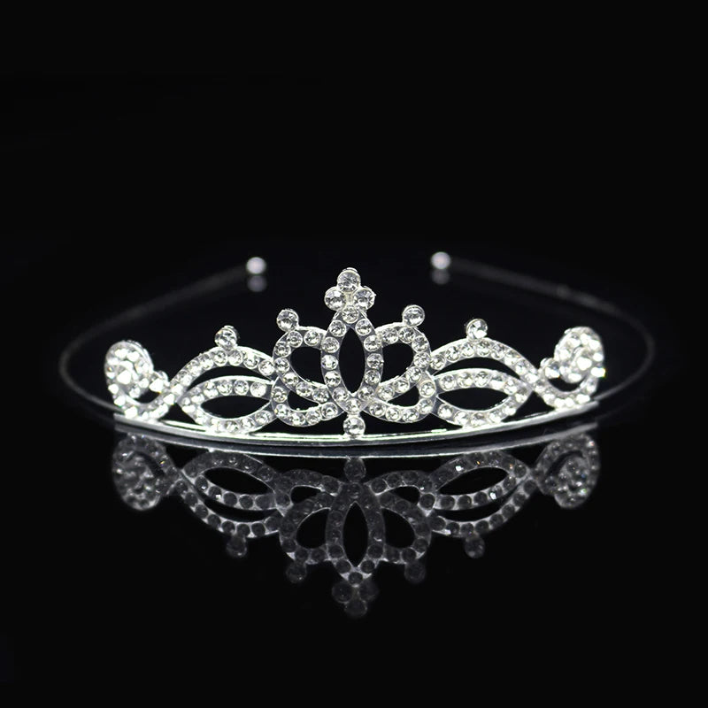 Tiara y corona de princesa de cristal brillante para el cabello, exhibida en una superficie reflectante.