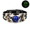Schwarzes Lederarmband mit silbernen Perlen, goldenen Akzenten und einem blauen Edelstein mit Löwenkopf-Design.