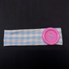 A light blue and white plaid fabric headband with a pink button attached.