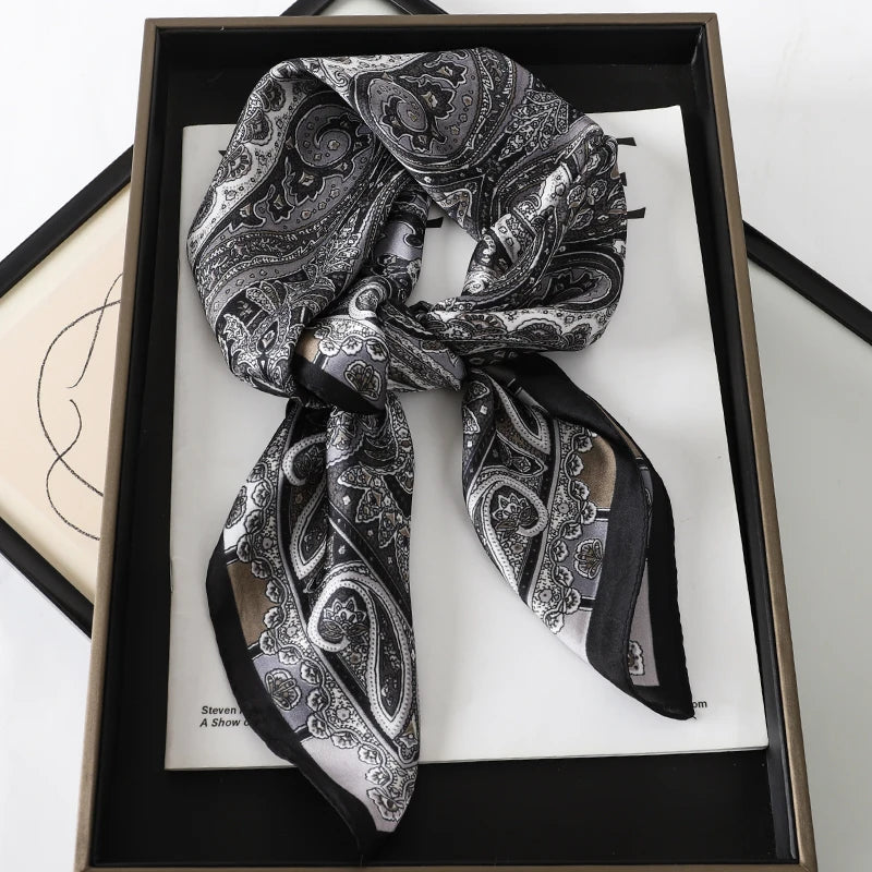 A black and white patterned silk scarf tied in a bow displayed in a wooden frame.