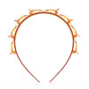 A round, orange braided hair headband clip with decorative elements.