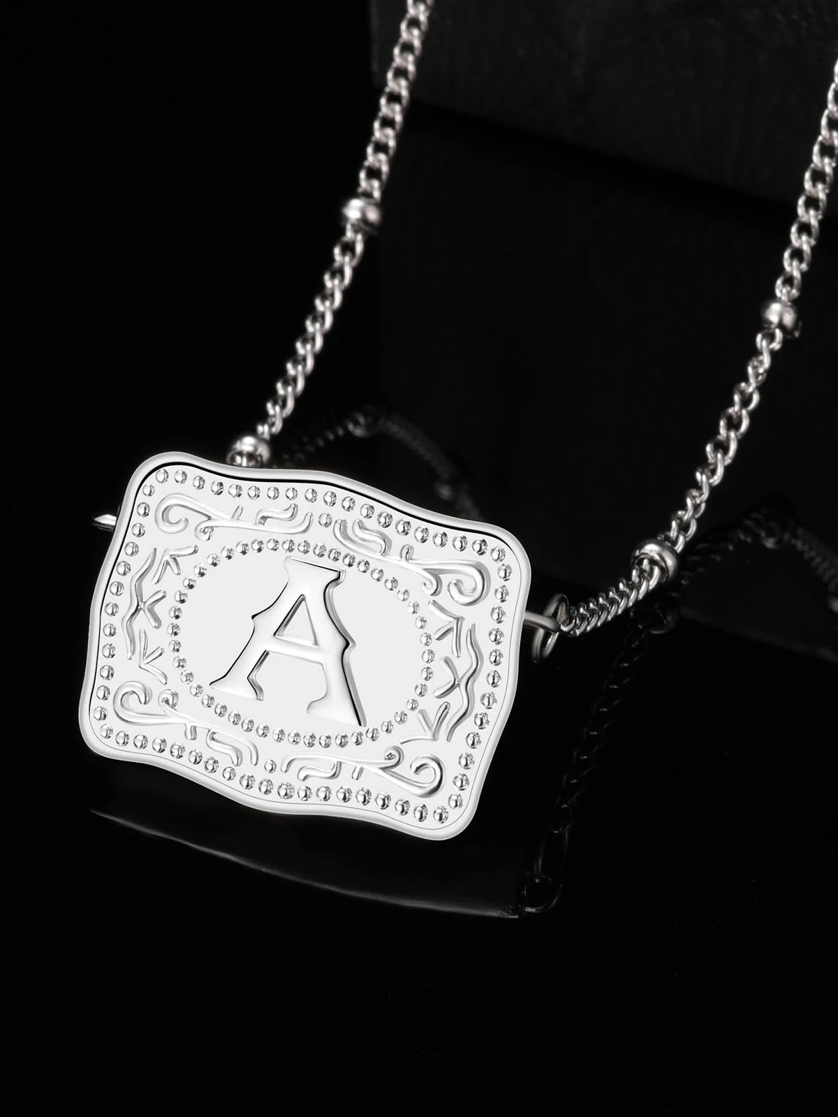 Silver pendant necklace featuring a large initial letter A surrounded by decorative scrollwork.