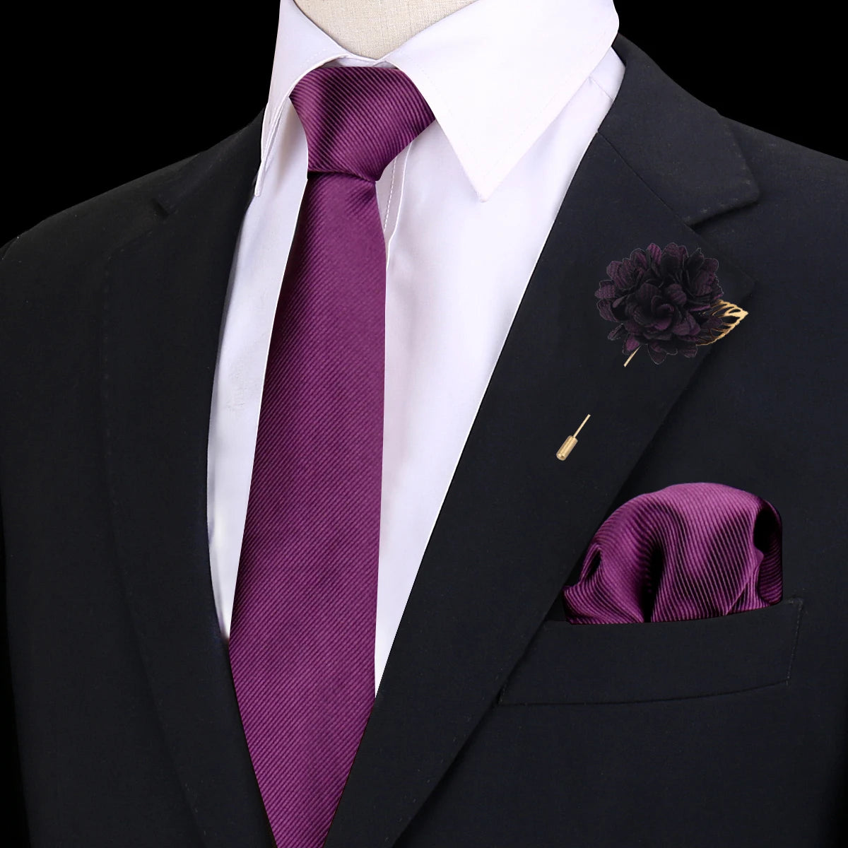 Una corbata de seda morada oscura con una camisa blanca y chaqueta de traje negra, con un prendido floral oscuro.