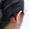A close-up of a person's dark hair with silicone anti-slip ear hooks attached to the back of the ear.