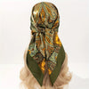 A close-up of a luxury satin silk scarf featuring an intricate pattern in shades of olive green, gold, and brown tied around 