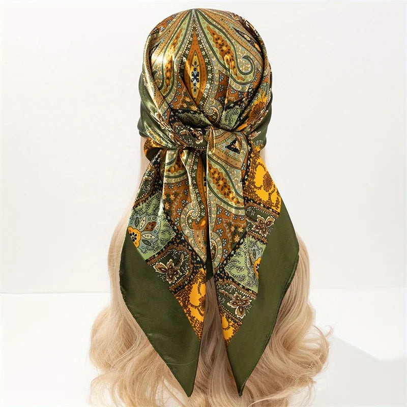 A close-up of a luxury satin silk scarf featuring an intricate pattern in shades of olive green, gold, and brown tied around 