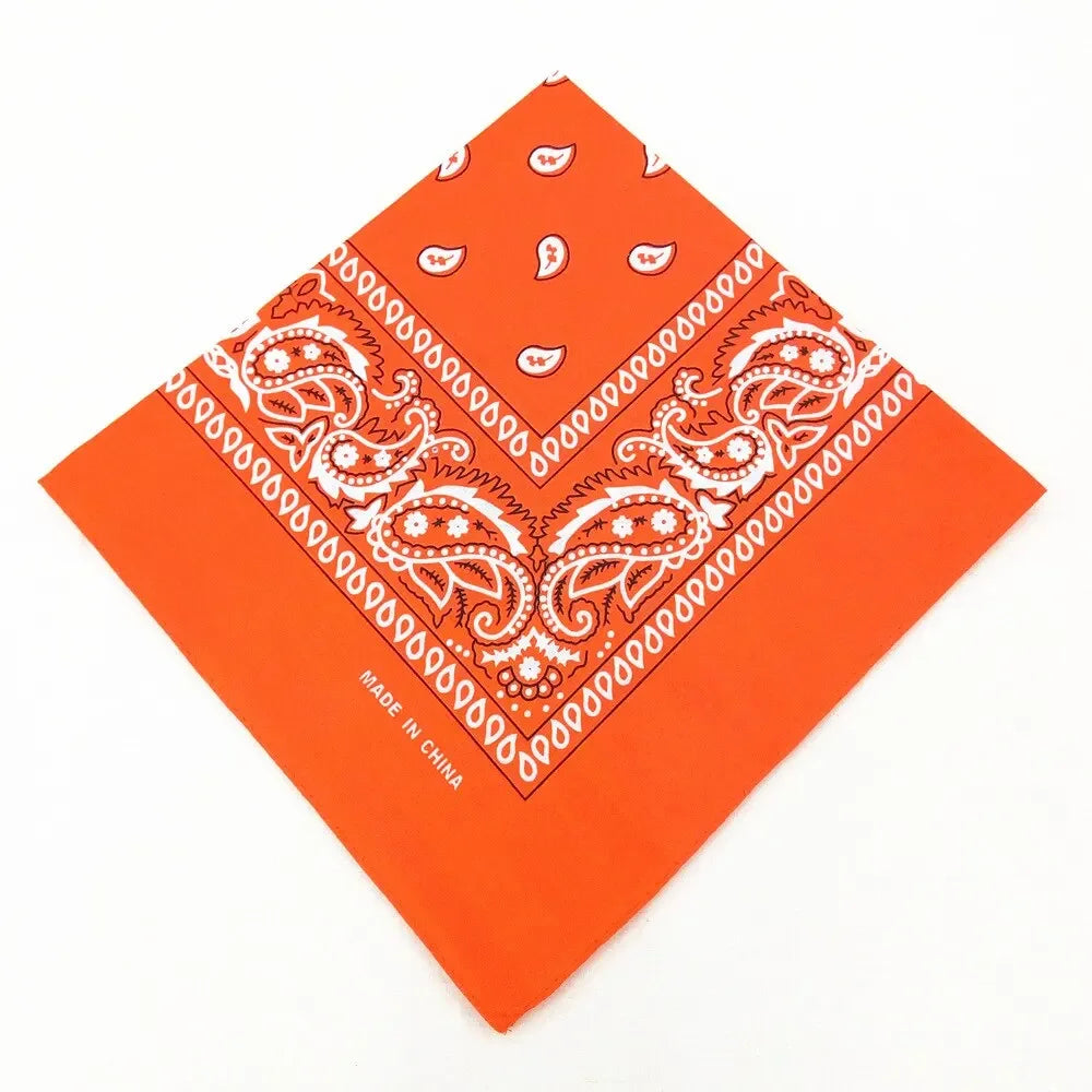Orange fabric bandana featuring white paisley and floral patterns, folded into a diamond shape.