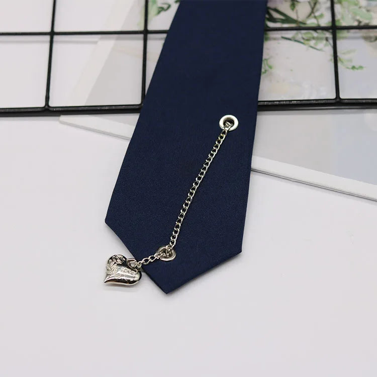 A silver chain necklace with a heart pendant is displayed against a dark blue necktie.