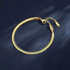 A gold double snake anklet with a chain and clasp is displayed against a dark background.