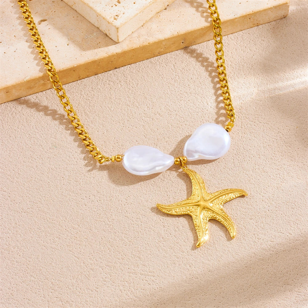 Gold chain necklace with a pearlescent heart pendant and a starfish charm on a light background.