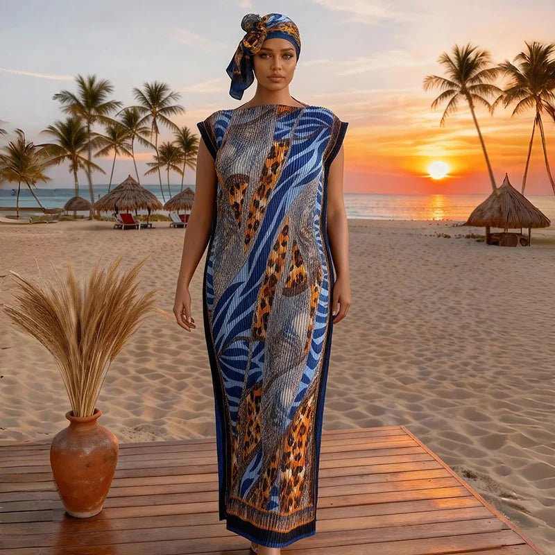 A plus size model wearing a blue and orange African silk printed maxi dress on a wooden deck near a tropical beach at sunset.