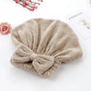 A soft, beige microfiber hair drying towel tied in a bow, placed next to some pink floral elements.