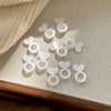 A collection of clear, heart-shaped and round silicone earring lifters for studs jewelry making placed on a light fabric surf