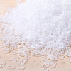 A pile of white disposable rubber hair ties for kids scattered on a light surface.