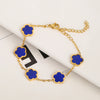 Pulsera de acero inoxidable chapada en oro con pequeños charms de flores azules en una cadena dorada.
