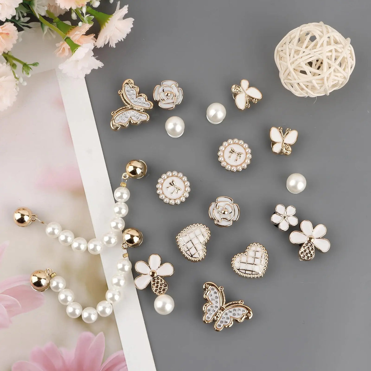 Colección de adornos para zapatos con pedrería brillante, incluyendo mariposas, flores y perlas, sobre fondo gris.