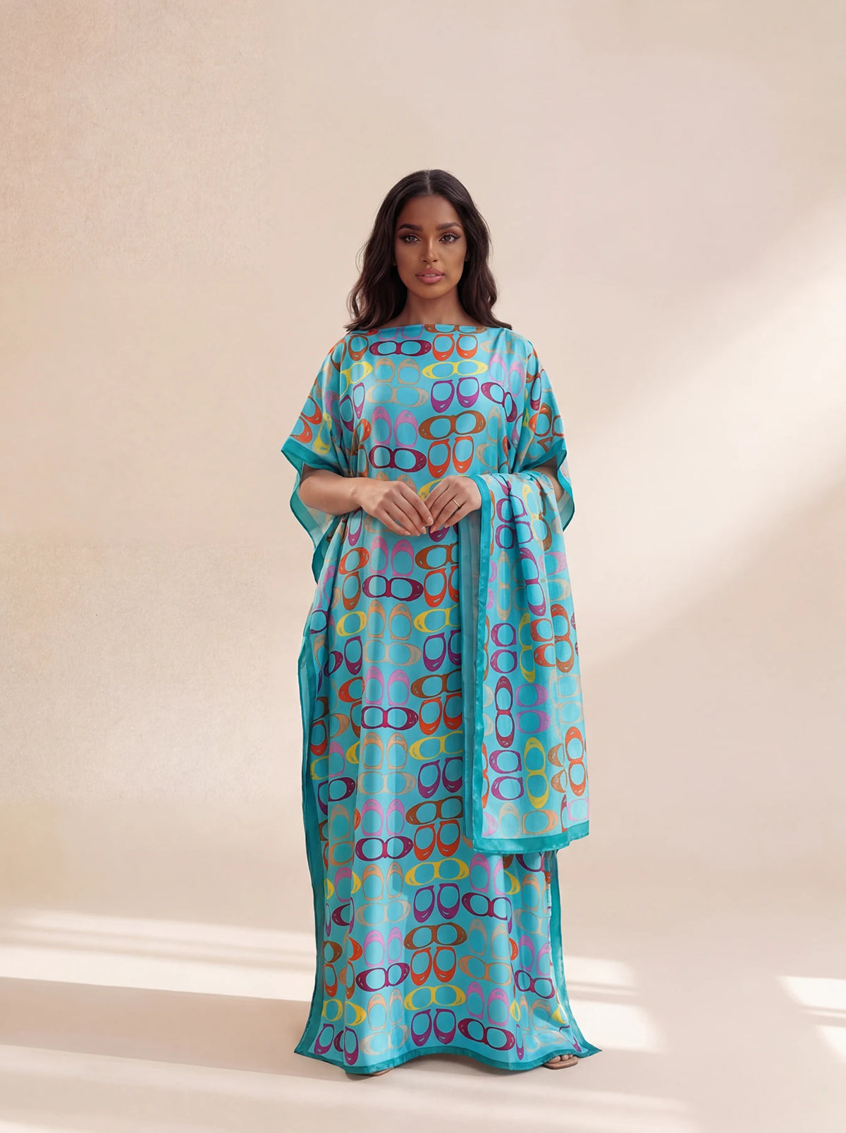 A woman models an elegant long silk blend cover-up robe dress featuring a vibrant blue and teal pattern with multicolored cir