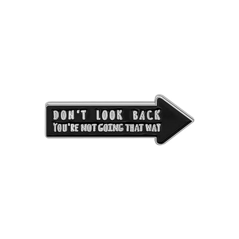 Black enamel lapel pin with text that reads Don't look back you're not going that way