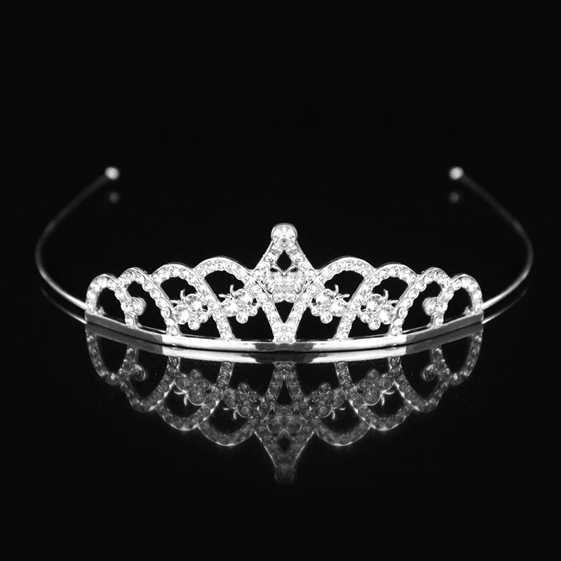 Tiara y corona de princesa de cristal brillante para el cabello, exhibida sobre una superficie reflectante.