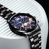 A close-up shot of a black stainless steel quartz watch with a blue dial and gold accents resting on a white surface.