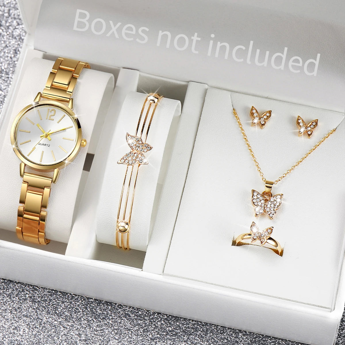 A white box contains a gold-toned quartz wristwatch, a gold-toned bracelet, and a gold-toned butterfly necklace and ring.