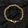 A gold-colored stainless steel twisted chain bracelet laid on a dark, textured surface.