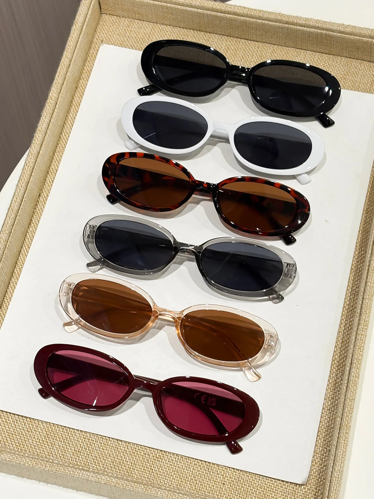 A collection of ten trendy leopard cat eye sunglasses in various shades of brown, black, and purple displayed on a white tray